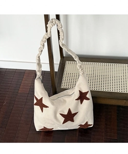 Close-up of star embroidery detail and ruffled strap on a cream canvas shoulder bag