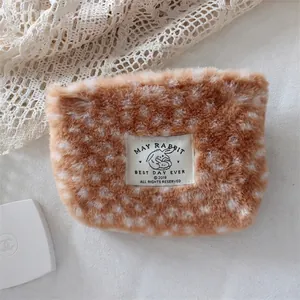 Detail of plush deer pattern makeup bag with a woven label and soft faux fur texture