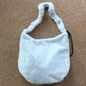 Detail of soft ice blue plush shoulder bag with textured faux fur and curved strap