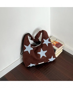 Close-up of star embroidery detail and ruffled strap on brown suede tote bag