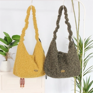 Close-up of fluffy plush tote bags with twisted handles and metallic brand tags