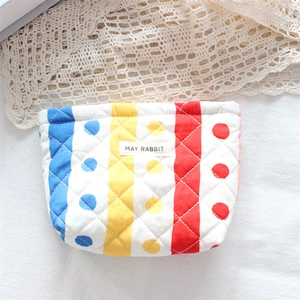 Detailed macro view of quilted floral makeup bag with colorful stripes and fabric label