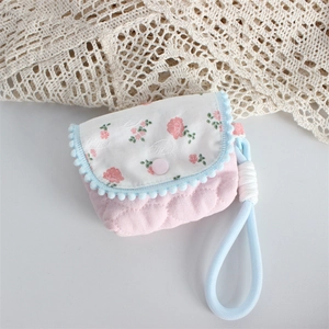 Detail of pink quilted fabric case with floral lid and pom-pom trim for CC camera