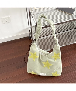 Detail view of light green canvas tote with yellow star patch and ruffled shoulder strap