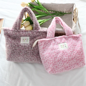 Leopard print plush handbags in pink and brown shown with tulips and a woven basket