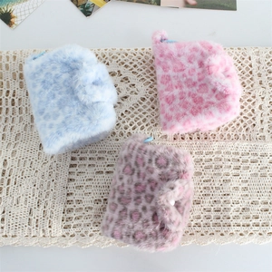 Detailed view of plush leopard print coin purses in blue, pink, and grey on lace fabric