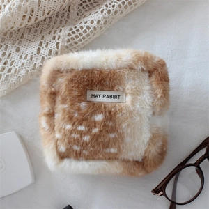 Macro detail of plush faux fur storage bag with brown and white deer pattern and label