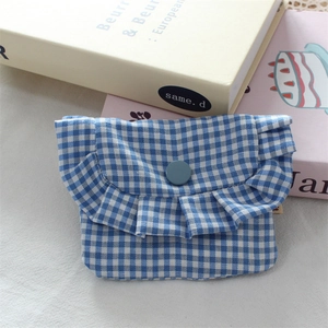 Detail showing blue gingham pattern fabric with ruffled edge and button on mini storage pouch