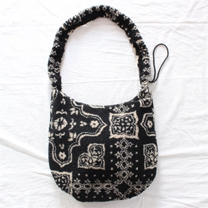 Detail of plush crossbody bag featuring black and white ethnic floral patterns and wide strap