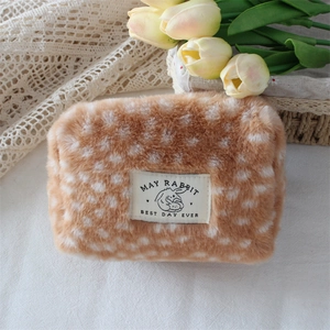 Macro shot of plush fawn pattern makeup bag showing soft texture and rabbit woven label