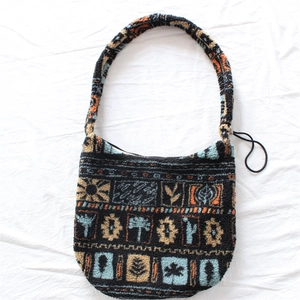 Detail of plush crossbody bag featuring colorful retro ethnic sun patterns and textured fabric