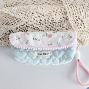 Macro detail of quilted heart pattern with floral flap and decorative pink pom-poms