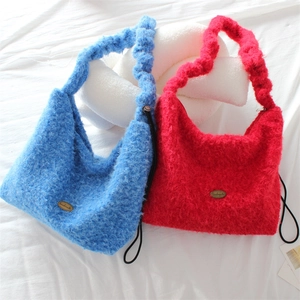 Fuzzy plush tote bag in vibrant blue and red colors with handmade metal logo detail