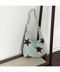 Detailed close-up of mint green suede bag with brown star embroidery and ruffled strap