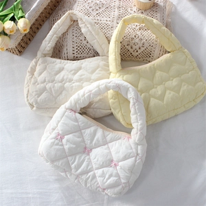 Close-up of quilted handbag featuring heart patterns and cute pink bows on soft fabric