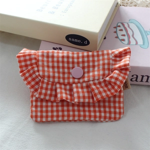 Close-up of orange plaid mini storage pouch with ruffle trim and snap button closure