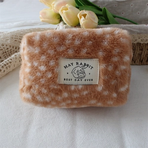 Close-up of soft deer print plush cosmetic bag featuring a rabbit woven label on lace