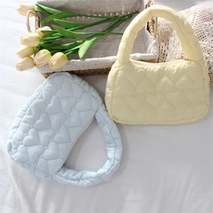 Detailed view of quilted heart patterns on soft pastel yellow and blue mini handbags