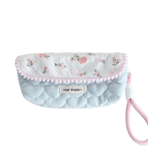 Quilted floral pouch with heart patterns, pom-pom trim and pink carrying strap