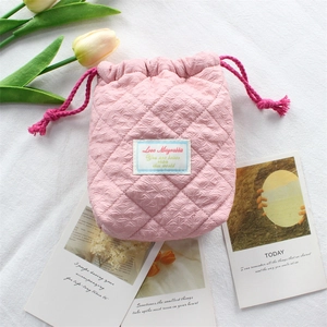 Detailed view of pink quilted fabric texture and drawstring closure on camera storage bag