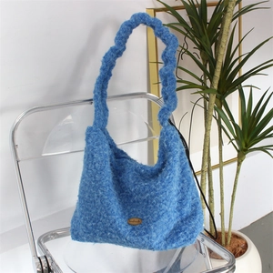 Detail of blue plush tote bag featuring handmade leather label and wavy handle
