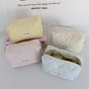 Detailed heart quilted makeup bags in yellow, pink, beige and blue with zipper closure