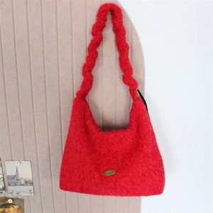 Close-up of fluffy red plush tote bag with a golden handmade oval metal plaque