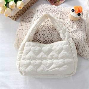 Close-up of cream heart-quilted handbag on lace with tulips for a fresh aesthetic
