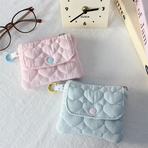 Detail of quilted heart pattern wallets in pink and blue with snap closure and strap loops