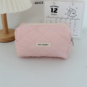 Close-up of pink quilted heart makeup bag featuring a silver zipper and brand woven label
