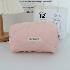 Detailed close-up of pink quilted heart makeup bag with May Rabbit label on desktop