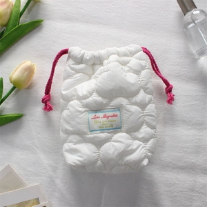 Macro detail of white quilted camera pouch with pink drawstring and soft cloud texture