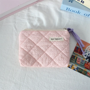 Detailed top view of pink quilted fabric coin purse with purple zipper pull on white surface
