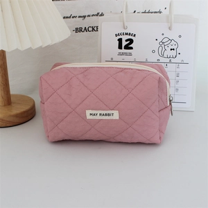 Detail of pink quilted makeup bag showing soft embossed heart patterns and zipper closure