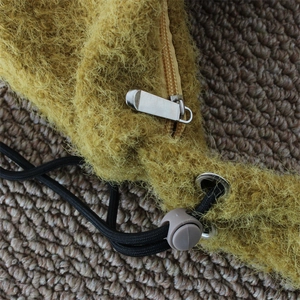 Macro detail of mustard yellow plush bag fabric with silver zipper and drawstring toggle