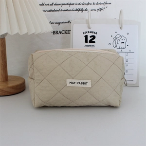Detailed close-up of quilted heart makeup bag with metal zipper and woven brand label