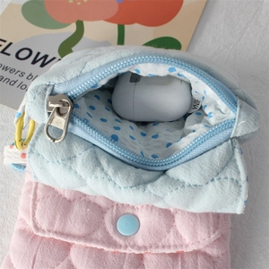 Close-up of heart-quilted cotton pouch with blue polka dot lining for wireless earbuds
