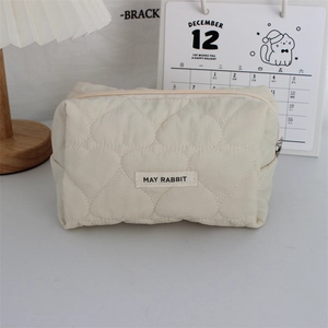 Detailed view of quilted heart pattern and zip closure on the cream makeup bag