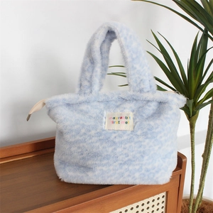 Close-up of plush blue tote bag featuring fuzzy texture and colorful logo patch detail