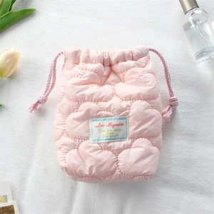 Detailed view of pink quilted camera pouch with purple drawstrings and decorative label