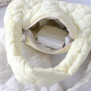 Detailed view of the quilted cream bag interior showing main compartment and inner pocket