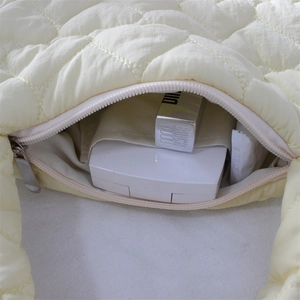 Detail view of the spacious inner lining and smooth metal zipper of the quilted handbag