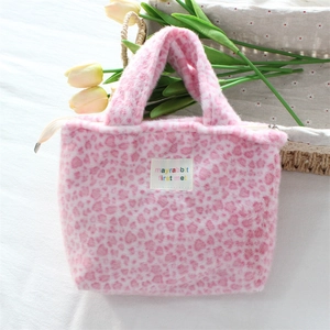 Detail of pink heart leopard print plush bag with a small woven label and zipper closure