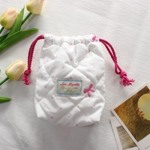 Detail of white quilted camera pouch with pink polka dots and drawstring closure