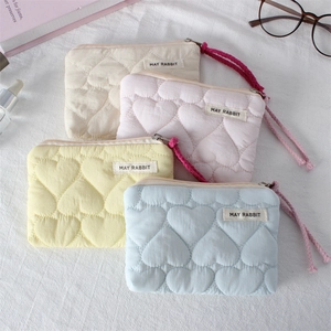 Macro shot of heart-quilted travel pouches in pastel colors with woven label detail
