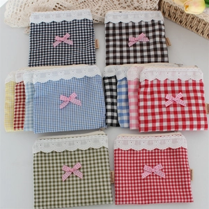 Dettaglio di pochette a scacchi colorate con bordo in pizzo bianco e fiocchi rosa