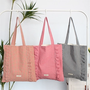 Détail de sacs fourre-tout à carreaux avec bords à volants en marron, rouge et noir