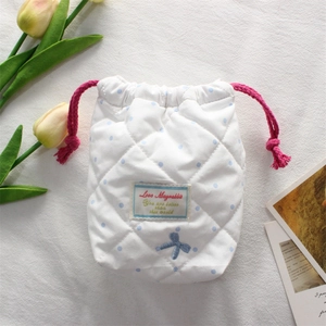 Detailed view of white quilted camera pouch with blue polka dots and a red drawstring