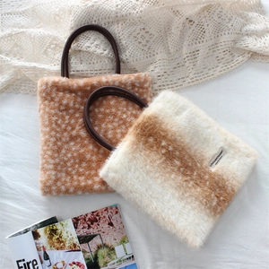 Detailed close-up of plush faux fur handbag with deer pattern and leather handle