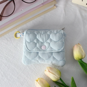 Detailed view of light blue quilted heart pouch with purple button and yellow ring hook